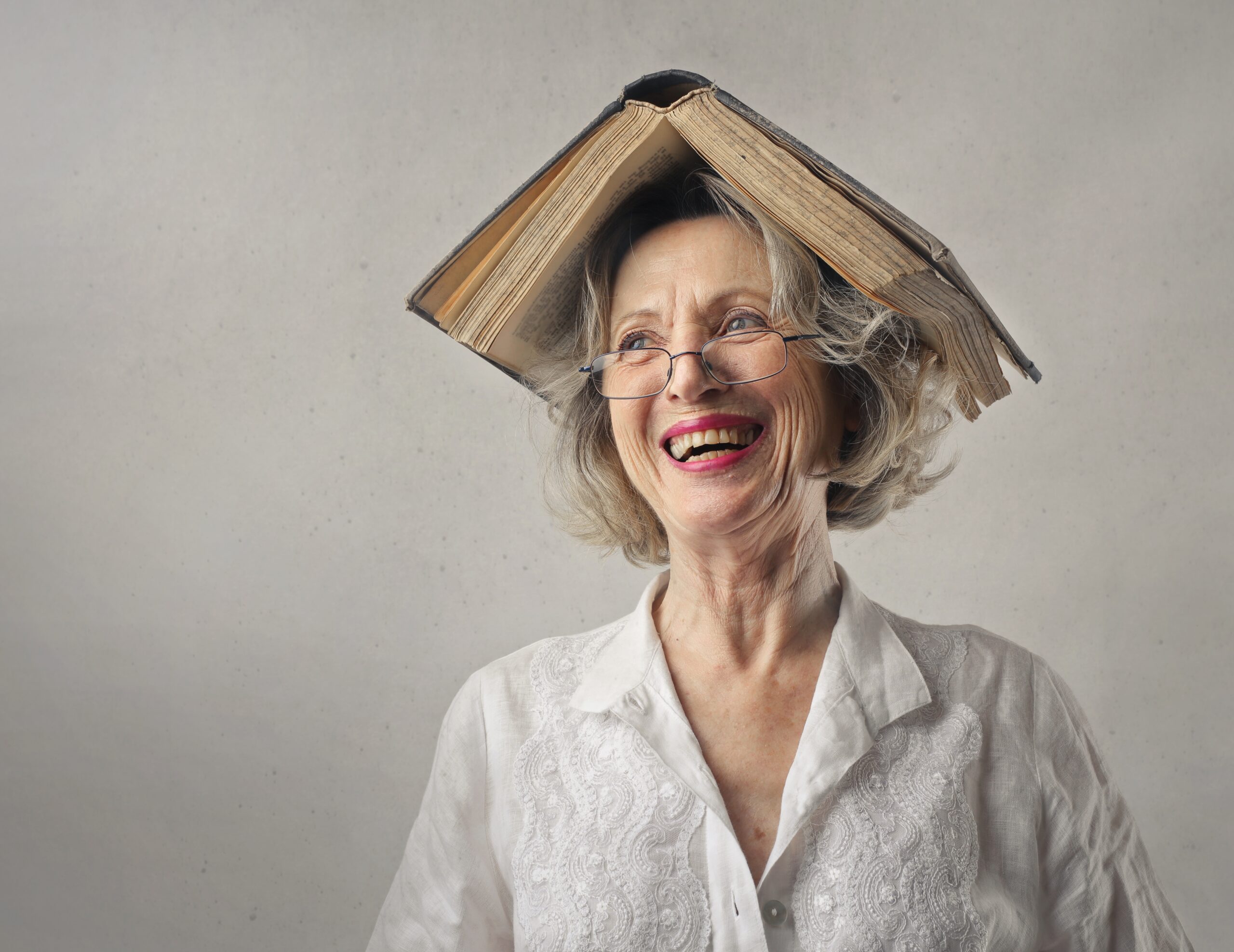Cheerful woman, laughing with a book on her head